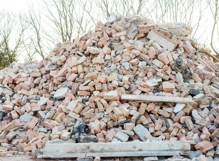Excavator removes construction waste after building demolition. Building rubble, bricks, stones. Junk, Garbage piled up. Street scene. Recycling industry, rubbish removal, and collection service