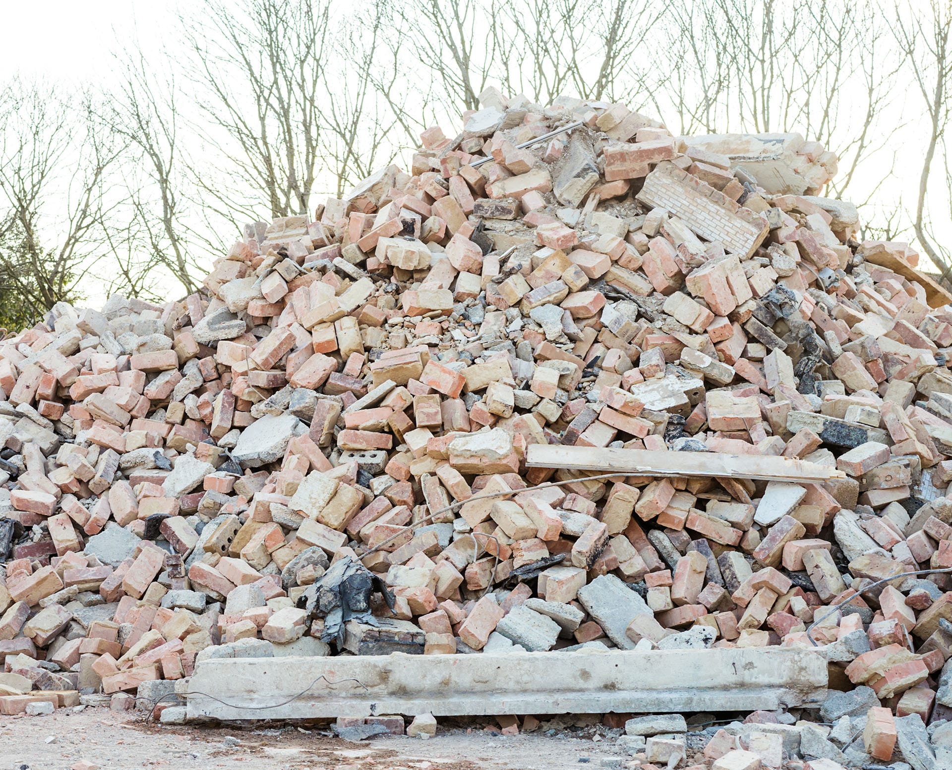 Excavator removes construction waste after building demolition. Building rubble, bricks, stones. Junk, Garbage piled up. Street scene. Recycling industry, rubbish removal, and collection service